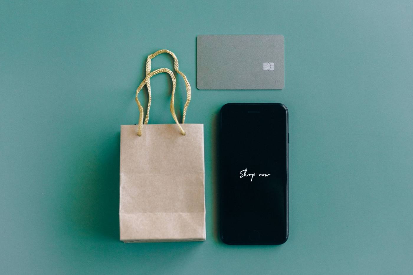 Ponsel dengan tulisan Shop now dan tas belanja